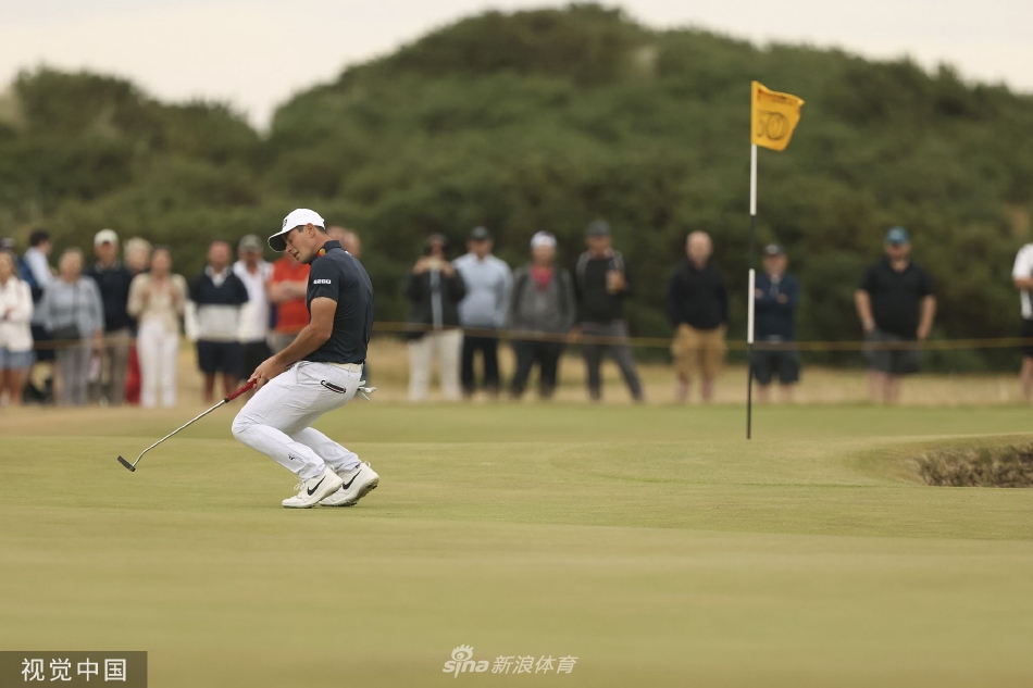 赛事工作人员高举第一百五十届英国公开赛的标志牌，走过古老的石桥，历史与现代在此刻交汇。