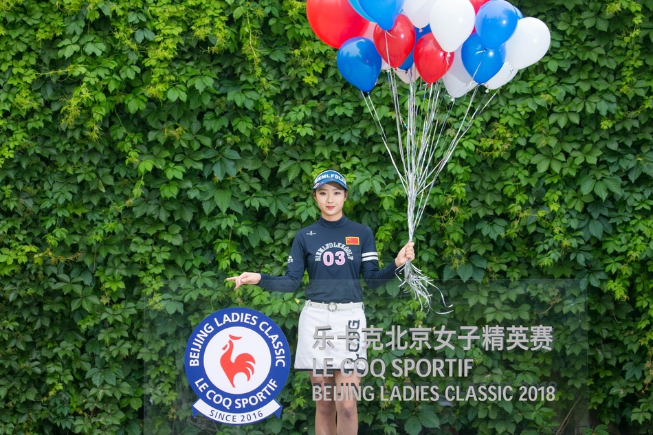 石昱婷在练习轮中优雅挥杆，白色上衣与蓝天绿草构成和谐画面