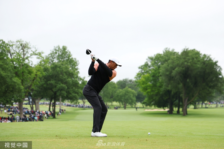老虎伍兹在强风中坚持行走，步伐蹒跚，但眼神依旧望向远方的球道。