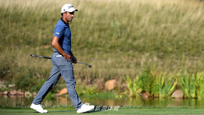 意大利名将埃多奥多·莫里纳利在信天翁球场第十八洞果岭边，凝神观察推杆线路，阳光勾勒出其专注的侧影。