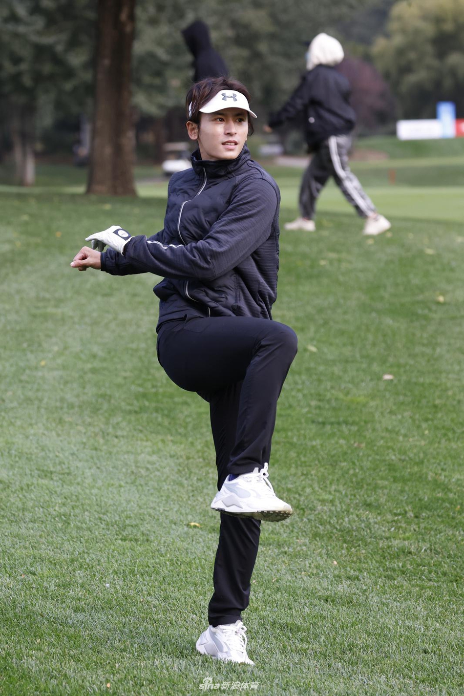 张哲瀚在练习推杆，他微微俯身，视线在球与球洞间牢牢锁定，侧影在阳光下显得格外修长而专注。