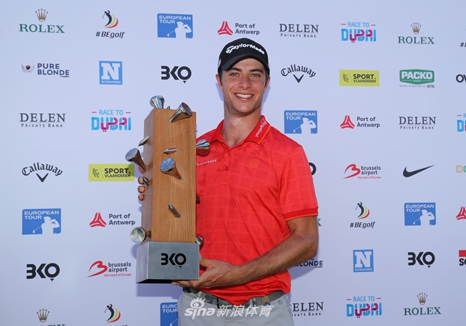 冠军米格里奥兹高举比利时淘汰赛奖杯，笑容灿烂，身后是绿草如茵的球场