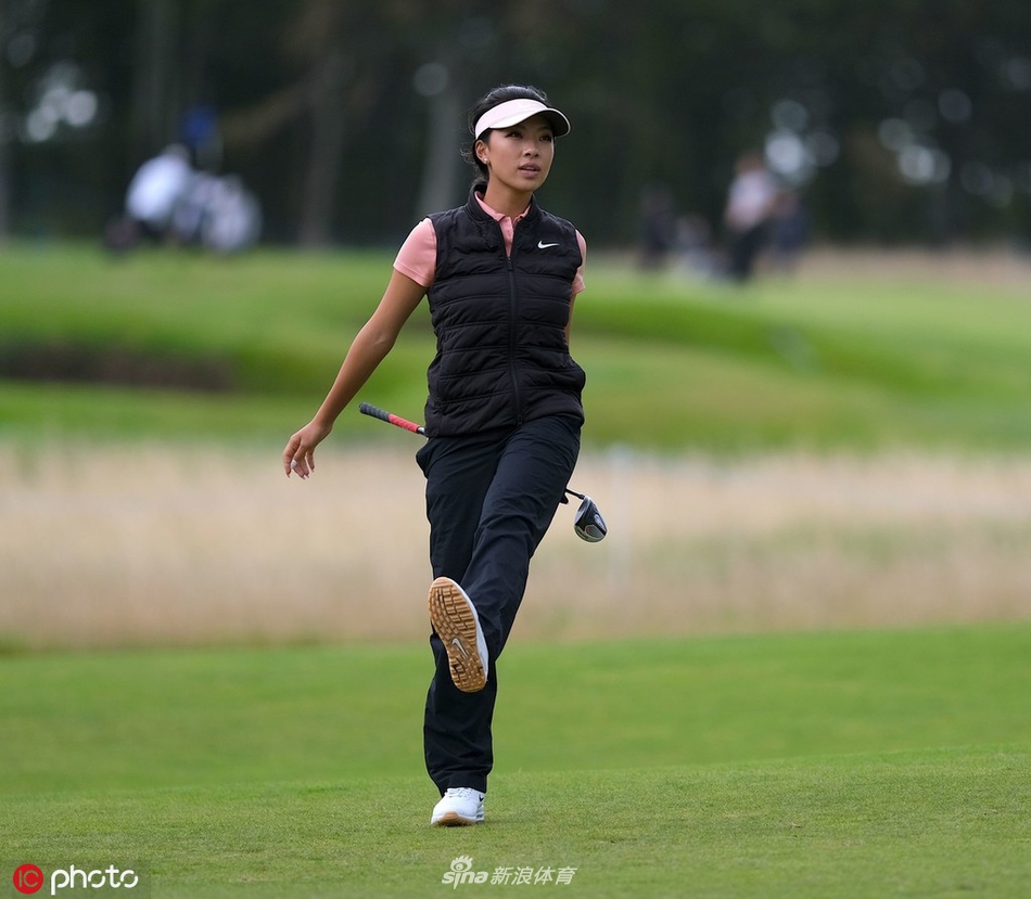 何沐妮在果岭边露出标志性的开朗笑容，阳光洒在她的身上