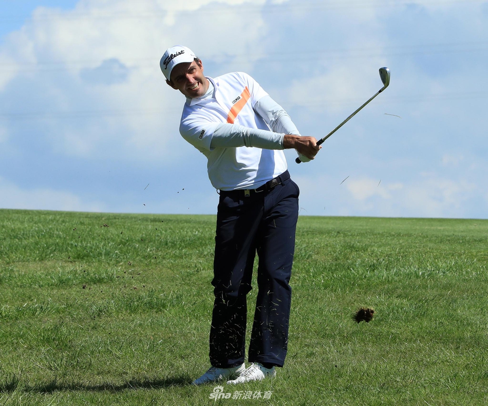 一位选手在强风中评估球位，表情专注，展现了职业高尔夫球手对抗恶劣天气的专业素养。