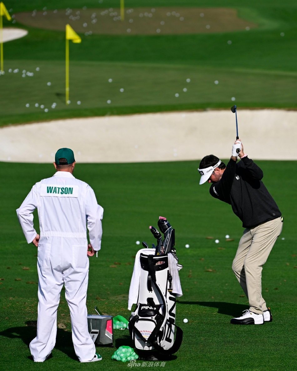 一位球星在练习果岭边凝神静思，绿夹克的身影与身后经典的白绿相间记分牌，构成一幅传承与专注的永恒画面。