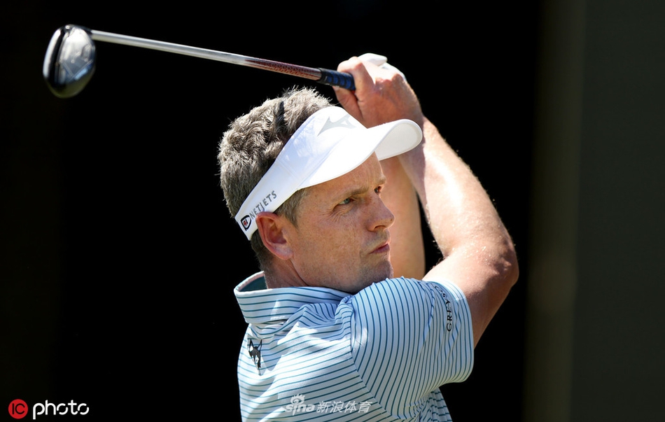 卡西的球童正俯身查看码数本，他脚上那双色彩鲜艳的大花袜子格外醒目，为紧张赛事增添了一抹轻松趣味。