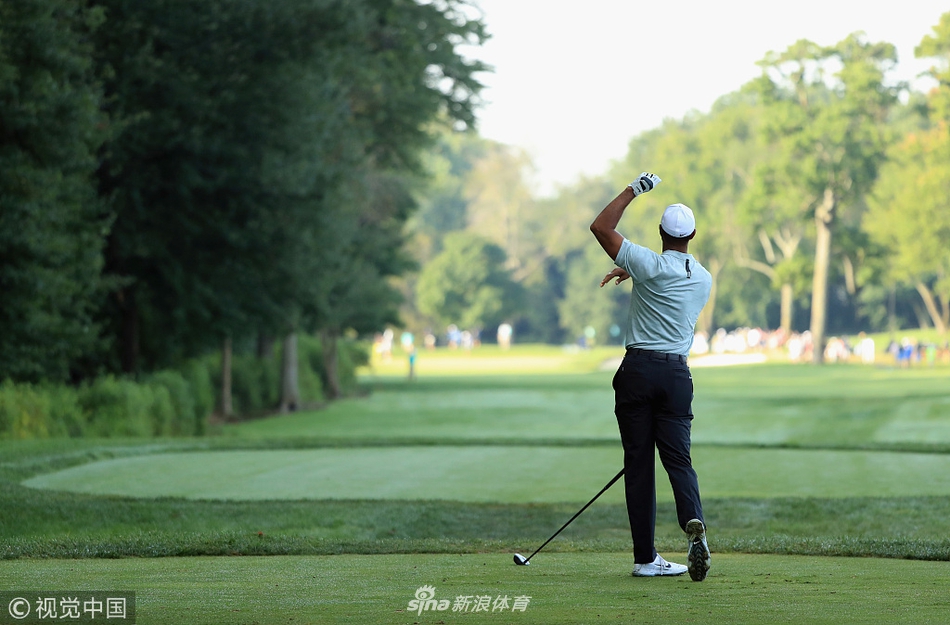 伍兹身着标志性红色Polo衫,在观众的注视下扛着球杆走在球道上,身影坚毅。