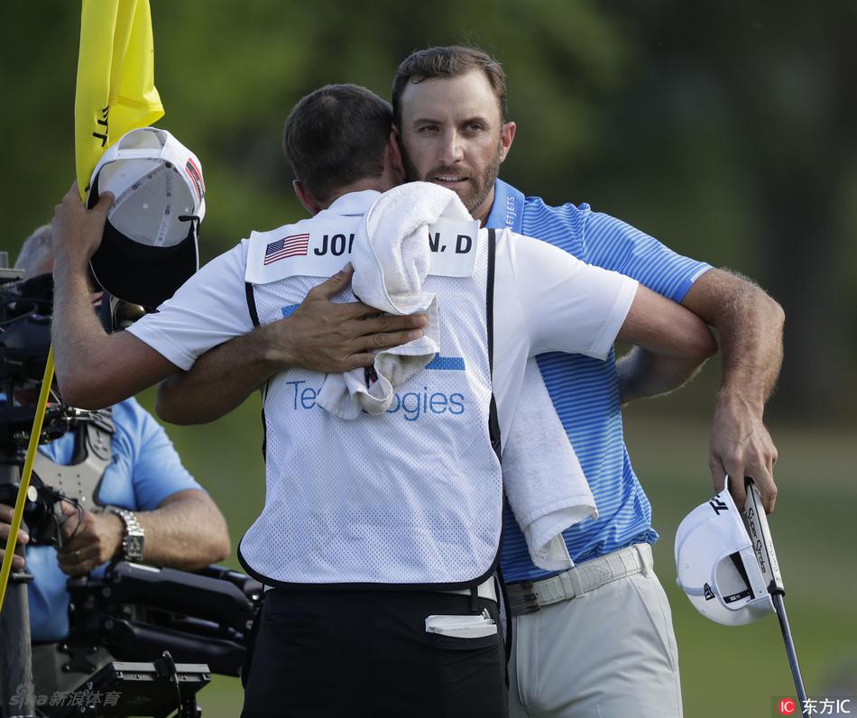 冠军达斯汀约翰逊怀抱奖杯，向观众致意，身后是见证历史的奥斯汀乡村俱乐部