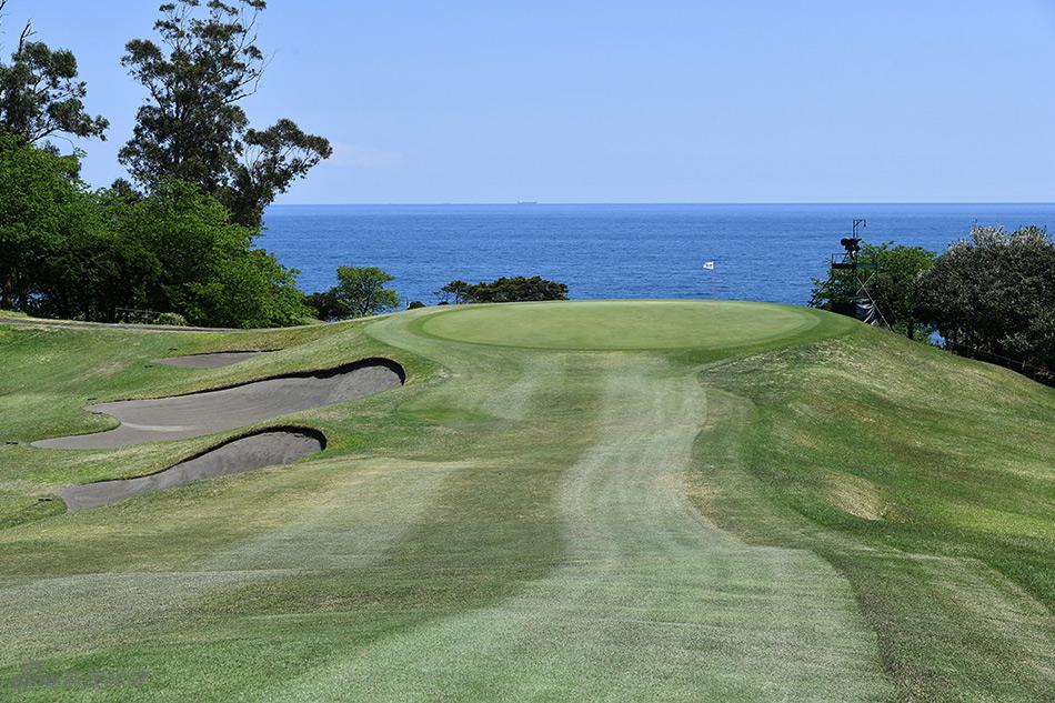选手在起伏巨大的球道上寻找落球位置，远处的山丘与近处的草坪形成富有挑战性的地形变化