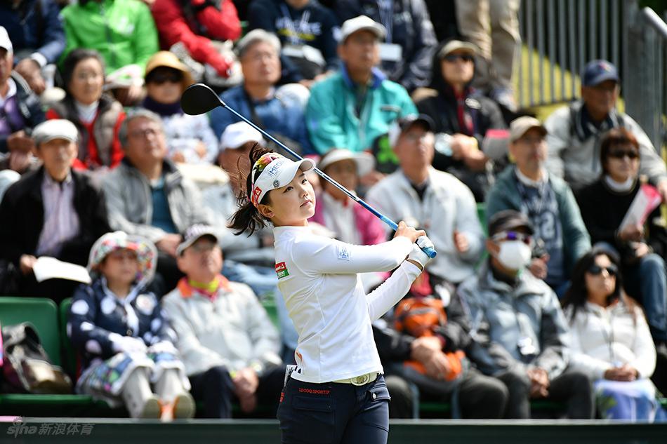 吉田弓美子与球童并肩站在发球台，两人手指远方果岭，正在认真商讨攻球策略