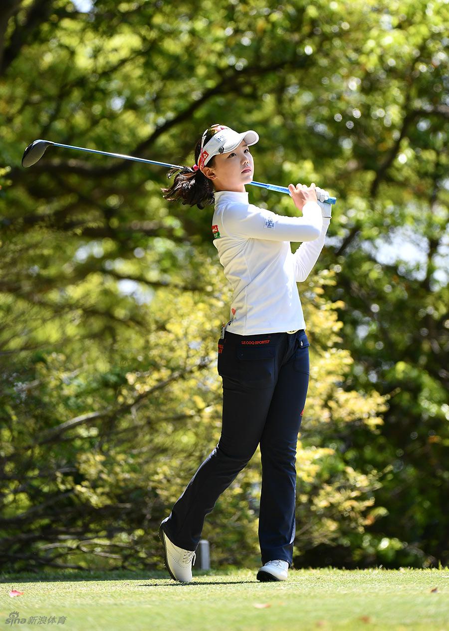 石昱婷在果岭边屈膝蹲下，从侧面专注地观察草地起伏与球洞线路，寻找最佳推杆路径