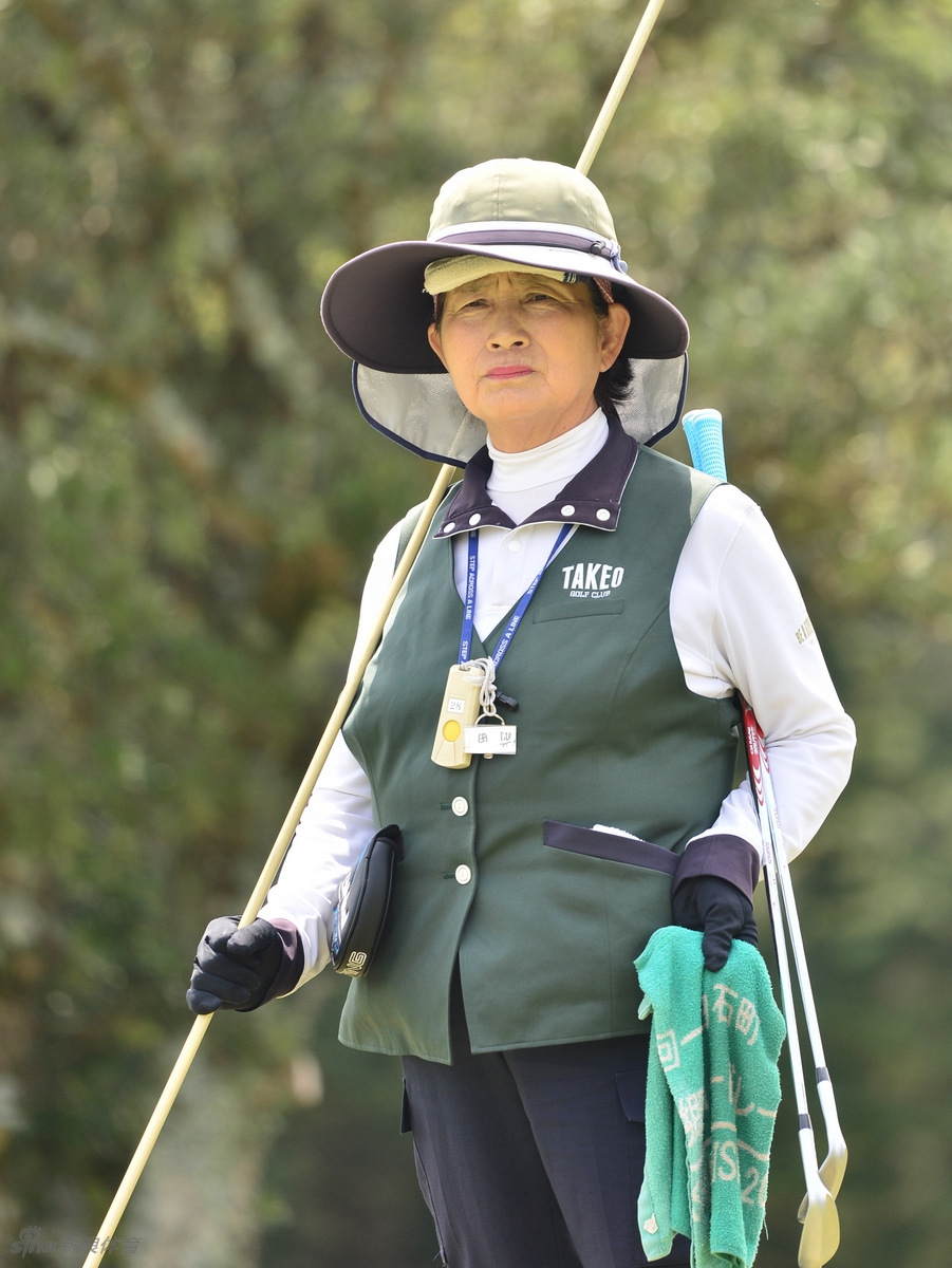 身为球场会员的志愿者面带自豪的微笑，正一丝不苟地为观众指引方向，他的热情是赛事服务最生动的名片。