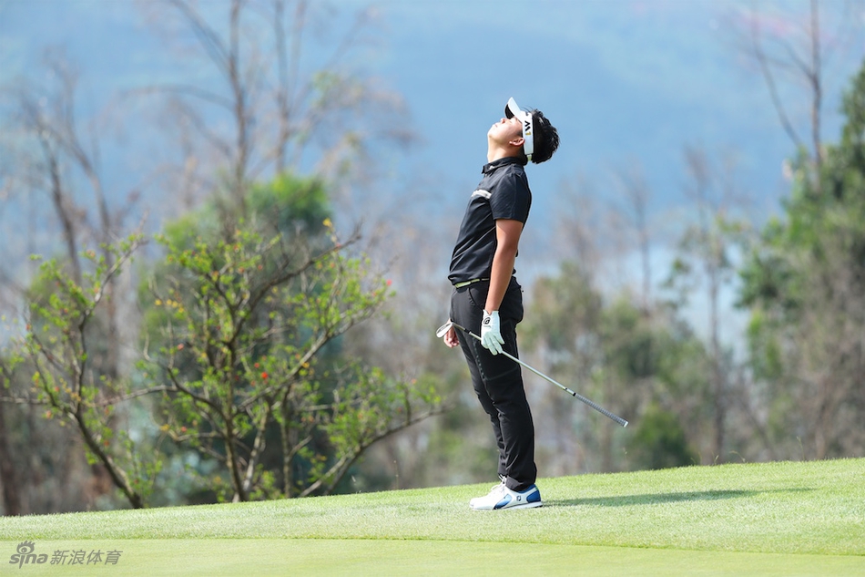 球员在果岭边观察推杆线路，跪姿查看地形细节，神情无比专注