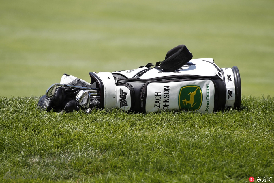 查德·坎贝尔与他的球童在果岭边弯腰仔细研读推杆线路。