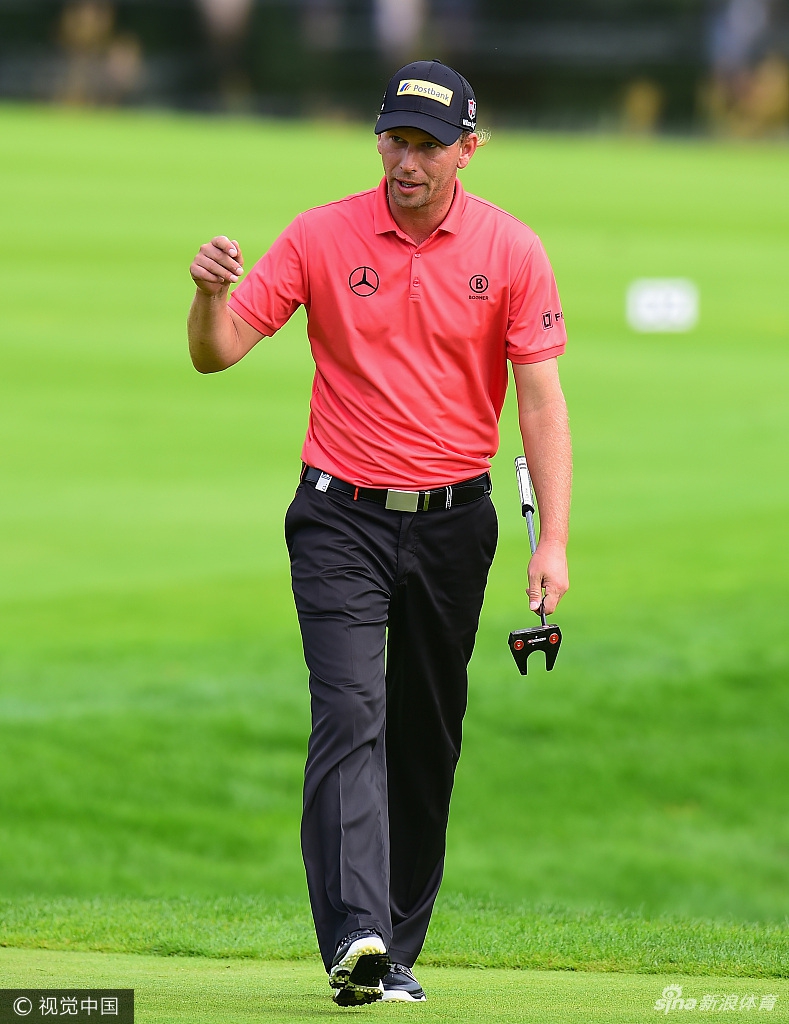 绿鹰高尔夫球场全景，球道在暴雨过后的积水中蜿蜒，天空乌云密布，展现出比赛环境的艰辛