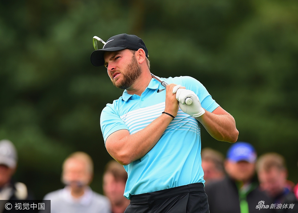 中国名将吴阿顺在球道上挥杆，动作流畅，身后是绿鹰球场标志性的浓密树林与长草区