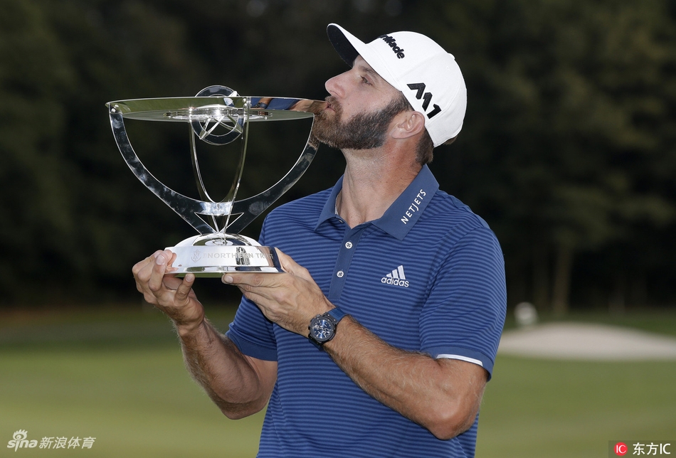 达斯汀双手高举奖杯，面带胜利者的灿烂笑容，身后是绿茵场与欢呼的观众。