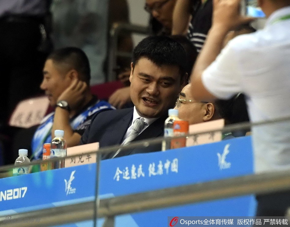 姚明结束沉思，目光如电般投向场内，面对场上胶着的比分和年轻球员的起伏，他的眼神中既有对精彩对抗的赞许，也有对未来的深远思考。