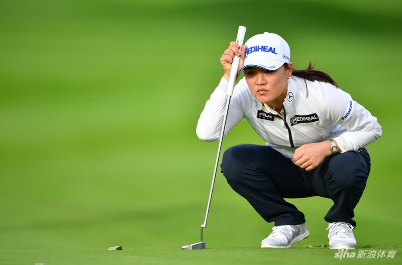 一位身着粉色服装的球员在练习果岭推杆，周围是标志性的粉色赛事装饰