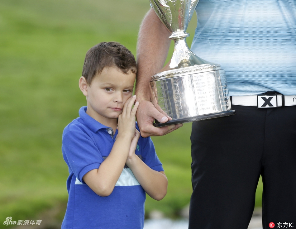 利什曼全家围绕奖杯灿烂微笑，背景是绿意盎然的球场和蓝天白云