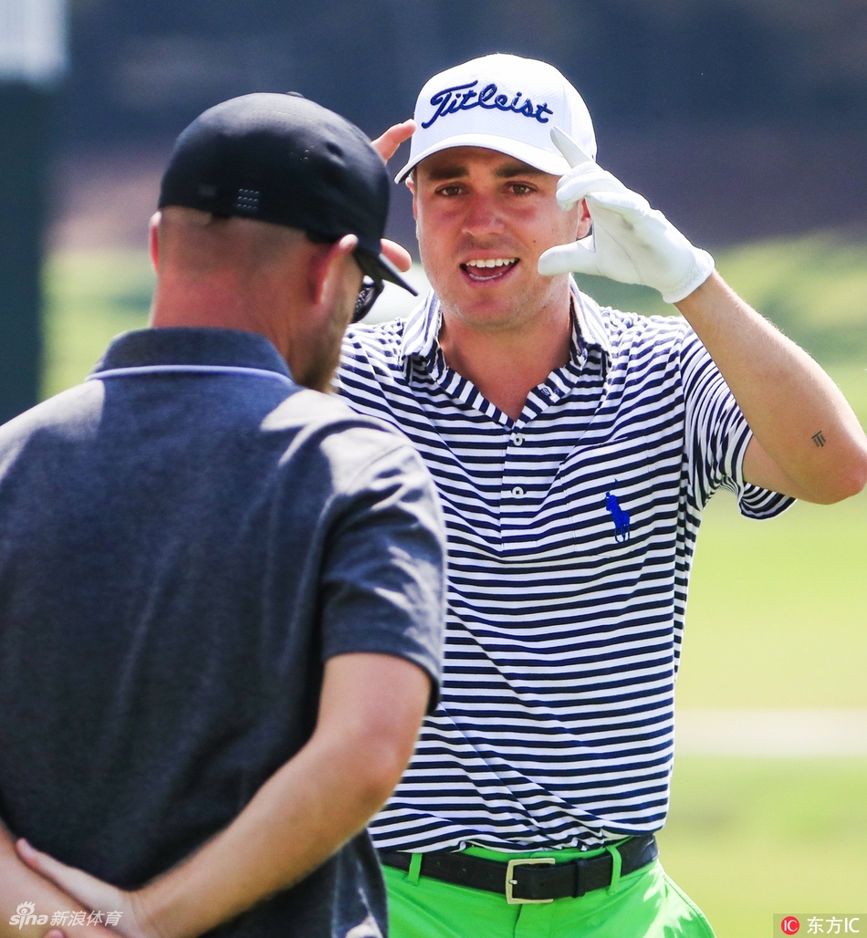 乔丹·斯皮思在练习果岭边缘专注地切击，目光如炬凝视小球飞行轨迹，身后翠绿的果岭与湛蓝天空构成鲜明对比