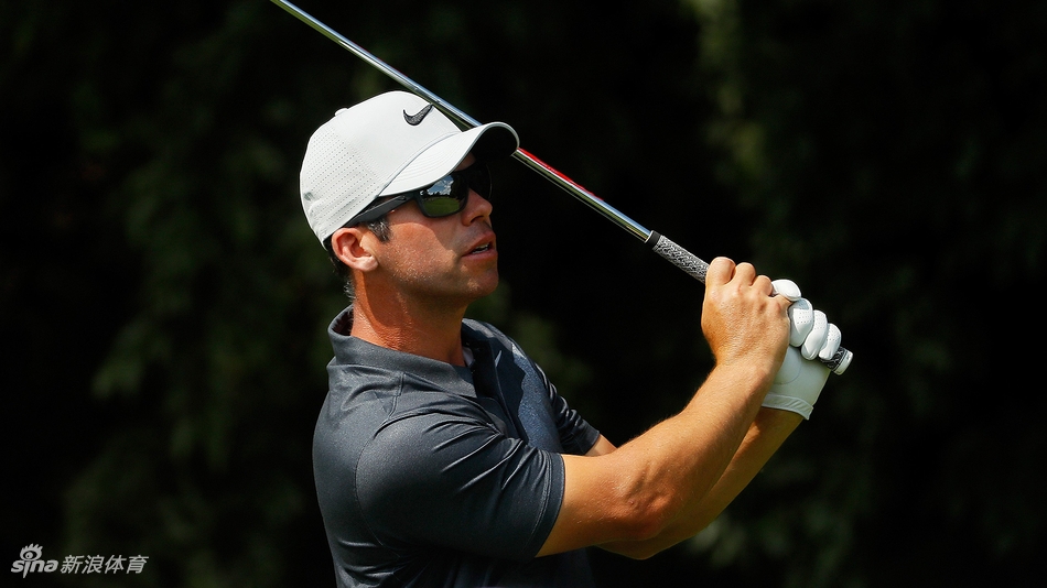 达斯汀·约翰逊侧身专注地注视着同组对手乔丹·斯皮思的开球动作，竞争氛围在静止的画面中悄然弥漫。