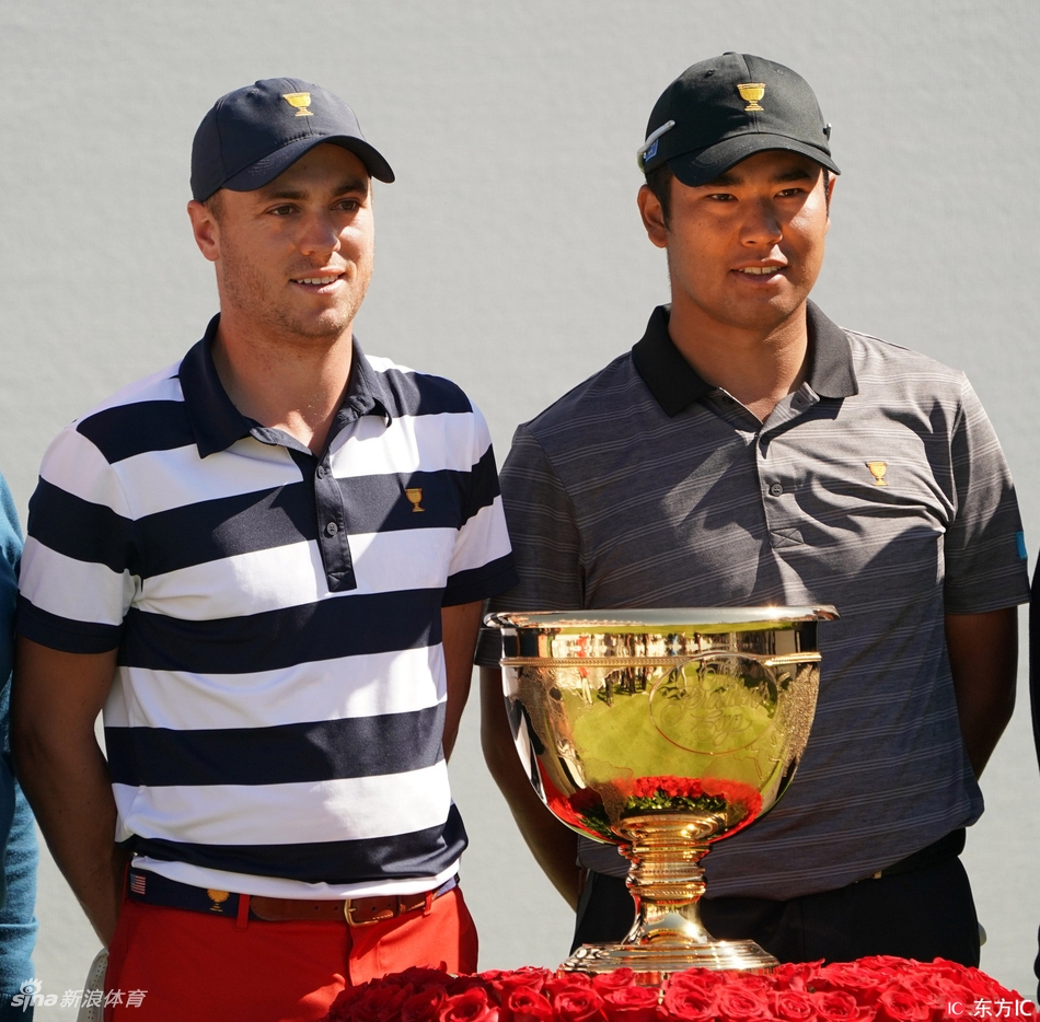 贾斯汀·托马斯与松山英树在果岭上并肩行走，进行着友好的交流，展现了竞技体育中珍贵的尊重与友谊。