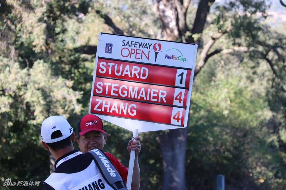 张新军与球童并肩研读果岭线路,专注神情中透出对胜利的周密筹划