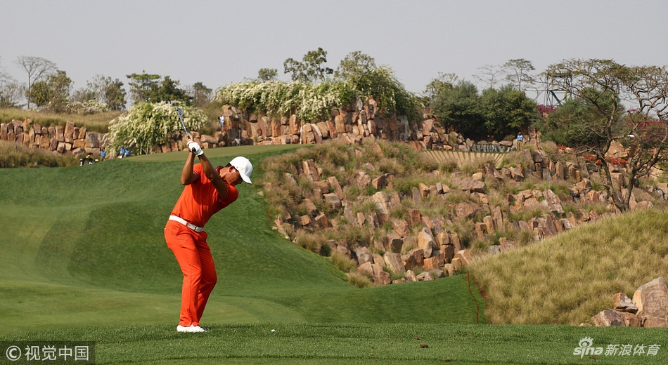 莱德杯队长比约恩站在练习果岭旁，双臂交叉，若有所思地观察着场上年轻球手们的表现。
