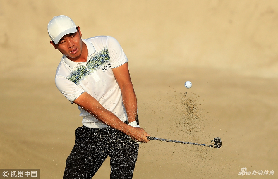 特写镜头下的沙坑，球杆击起一片金色沙浪，小球正从沙坑中跃向果岭，瞬间充满力量感。
