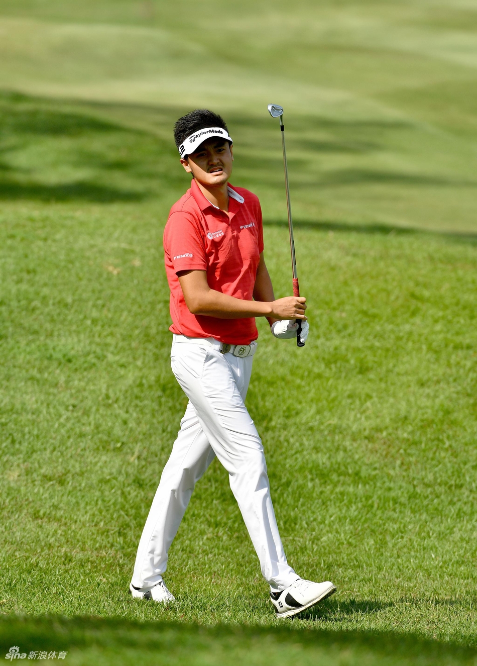 众多球迷聚集在果岭周边山坡上观看比赛，五彩斑斓的伞下是一张张充满期待的面孔