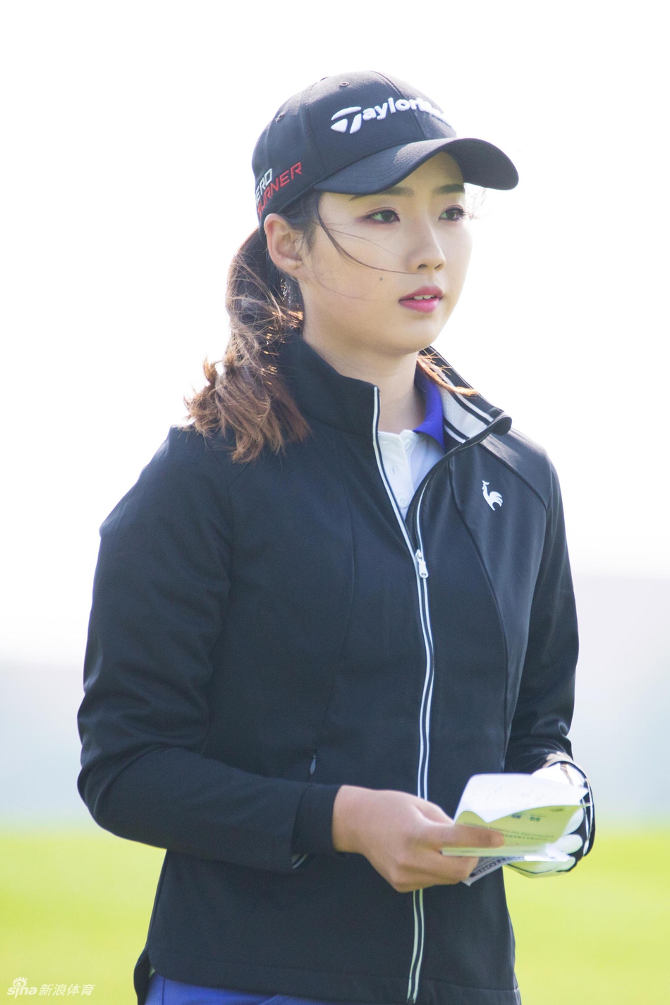 冀怡帆在教练的陪同下进行技术交流，两人手指向果岭方向，认真讨论着不同球位下的处理方案。