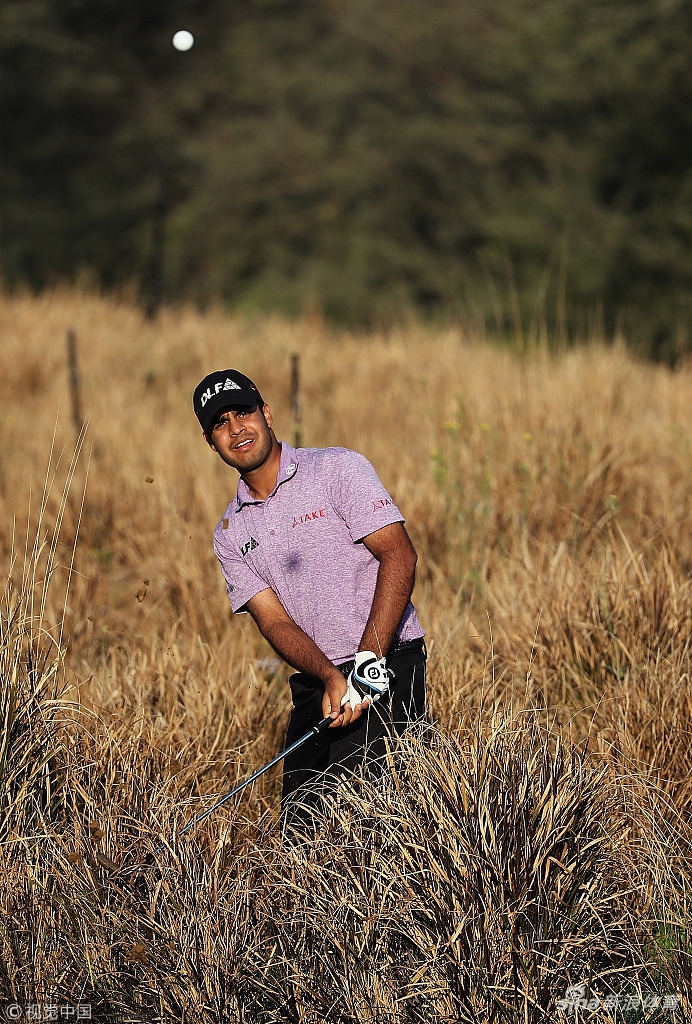 谷原秀人与他的球童蹲在球道边，两人头靠头仔细研究码数本，球童正用手指向果岭某处。