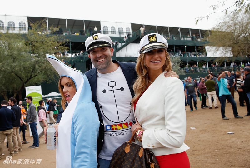 身穿奥古斯塔国家高尔夫俱乐部标志性白色连身裤的球童微笑着站在果岭旁，传统的高尔夫服饰与凤凰城公开赛的现代氛围形成有趣的时空对话。