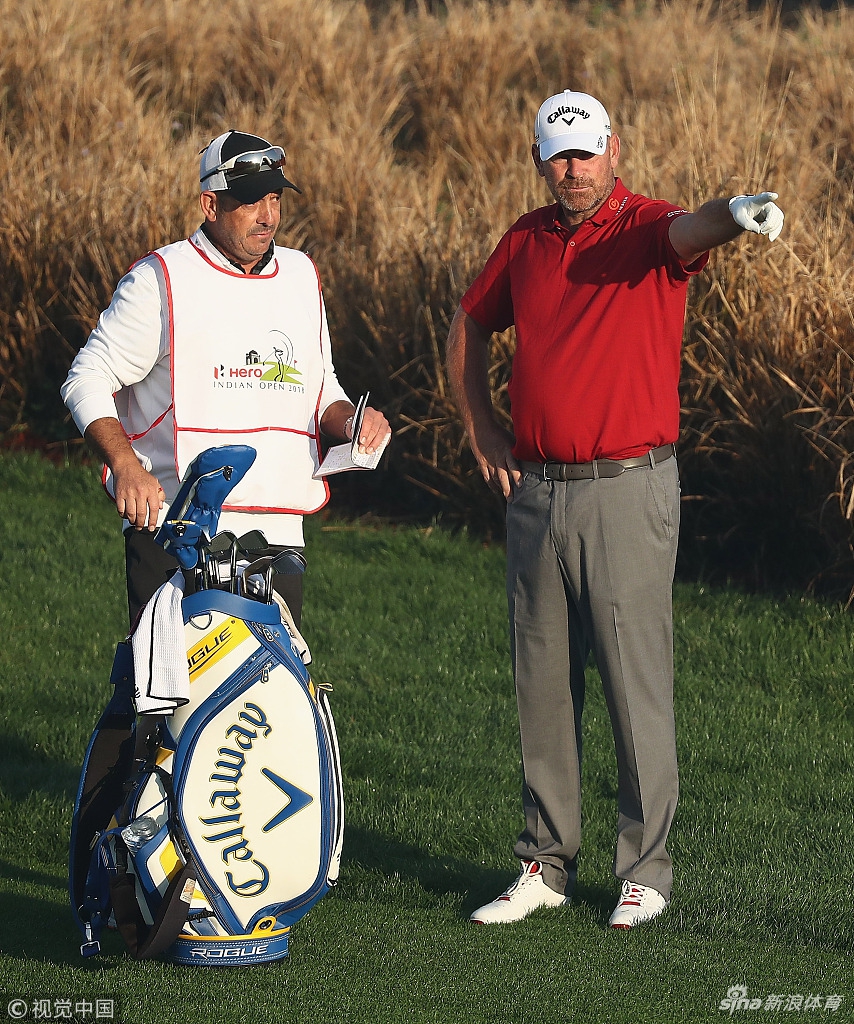 沙玛在长草中寻找球位，他眉头微蹙，手持铁杆准备处理困难球位，挑战显而易见。