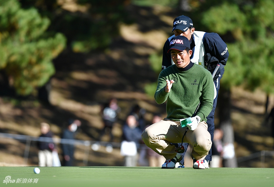 梁文冲在果岭上凝视推杆线路，表情沉静而坚定，正在为关键一推做最后准备