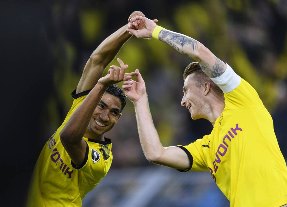 从另一个角度拍摄的庆祝瞬间，罗伊斯和阿什拉夫的手指紧紧相扣，背景是看台上涌动的人潮和炫目的灯光，将这个趣味时刻永久定格。