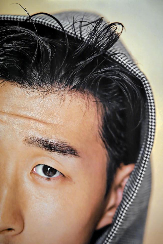 孙兴慜身穿一件极具设计感的亮色风衣，在动态抓拍中衣摆飞扬，与背景的模糊光影形成动感对比，充满艺术张力