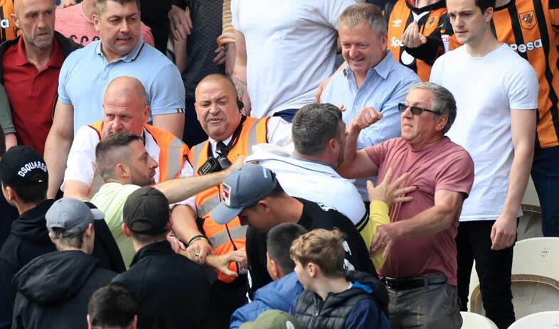 另一张图显示安保人员奋力冲入人群试图拉开失控的球迷，但冲突仍在继续，半空中有杂物飞扬，观众席上的其他球迷或惊恐躲避或高声叫喊，气氛紧张到了极点。