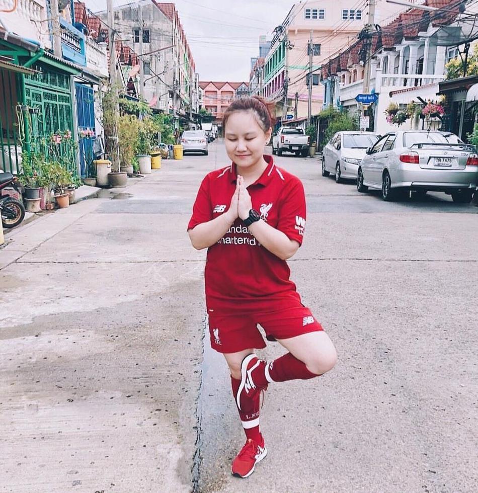 一位年轻的利物浦小球迷在家中客厅里，穿着萨拉赫的球衣，有模有样地模仿着偶像的莲花坐，脸上洋溢着满足而天真的笑容，仿佛此刻自己就是安菲尔德的主角。