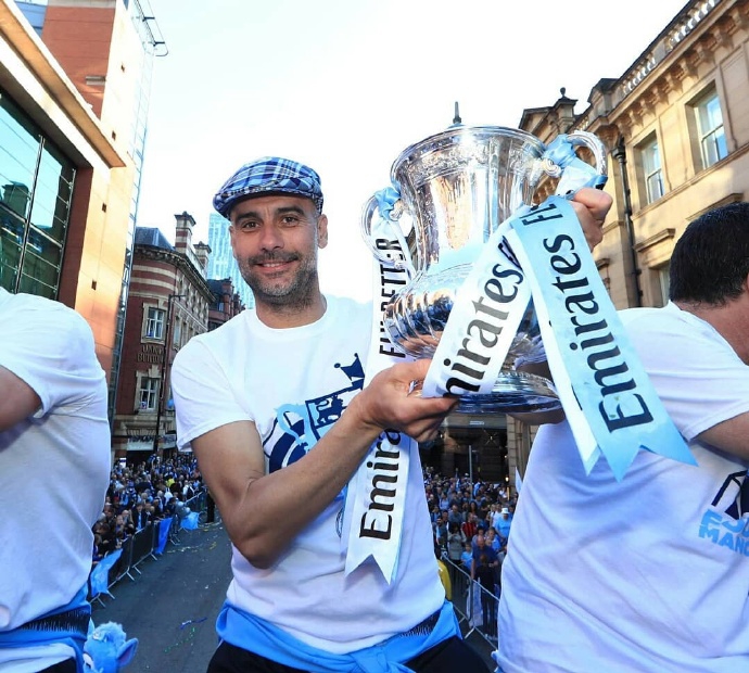 瓜迪奥拉手握麦克风，对着人山人海的球迷呐喊，表情既专注又充满力量，完美诠释了“霸气”二字的含义。