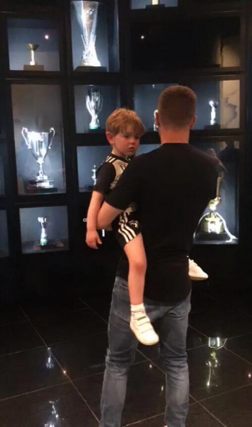 拉姆塞单手抱着儿子，另一手指向远方，仿佛在为他描绘未来在尤文图斯的蓝图。小家伙认真倾听的模样，就像一个小小男子汉在理解父亲的雄心。