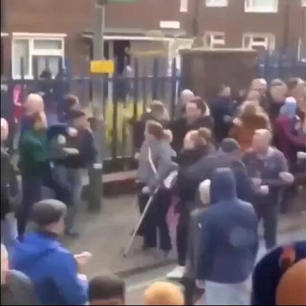 事件平息后，一名头部受伤的球迷坐在路边，用手捂着流血的伤口，身边站着几名警察在询问情况