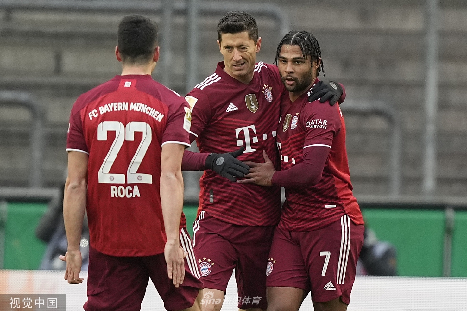 莱万多夫斯基进球后张开双臂，在科隆主场尽情庆祝，背景中拜仁队友正飞奔而来与他分享喜悦