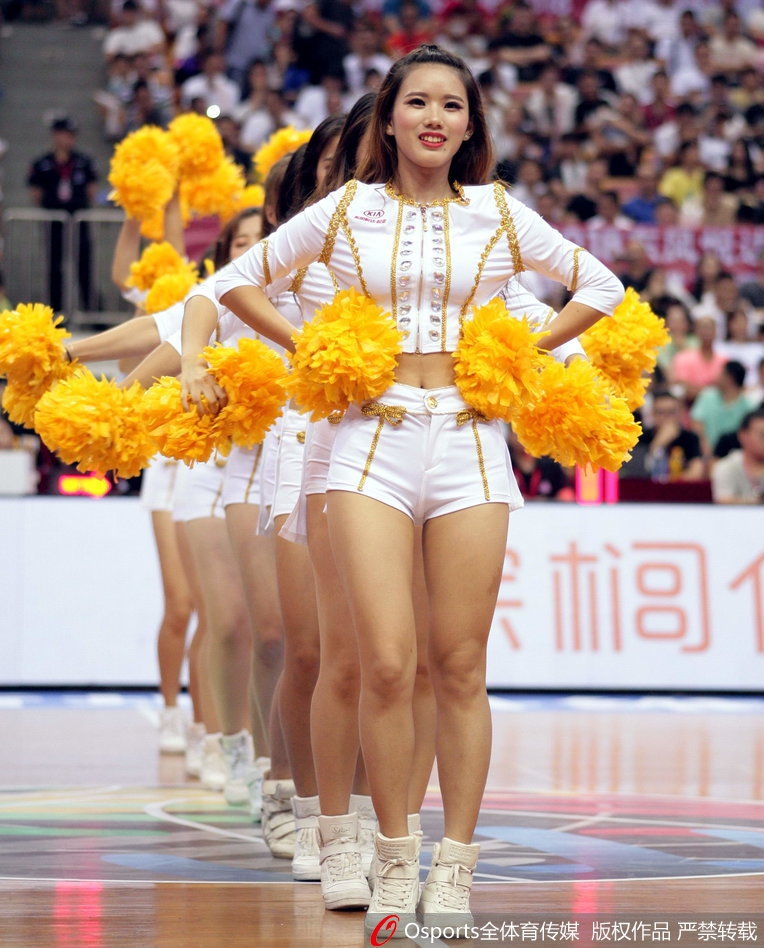 在灯光璀璨的赛场中央，一名宝贝单手叉腰，身姿曼妙，脸上带着自信的浅笑，背景是模糊的看台人群，她仿佛就是此刻全场的视觉焦点。