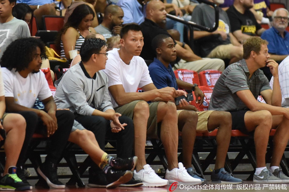 身穿浅色T恤的易建联神情轻松地坐在场边,目光柔和地望向赛场方向,仿佛一位老大哥在默默关注着弟弟的表现。