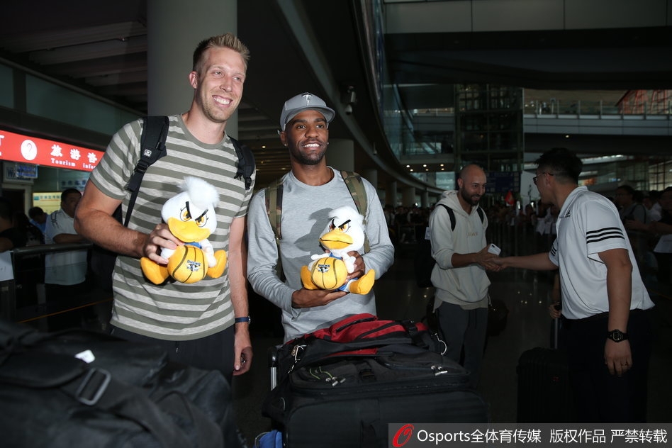 阿隆·杰克逊与汉密尔顿并肩而立，手中各自握着一只北京鸭吉祥物，两人相视而笑，仿佛在低声交流着对新赛季的无限遐想。