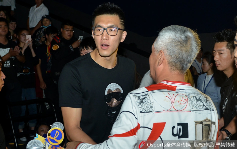 导演大鹏在沈阳首映礼上发言,身旁站着主演乔杉等人,背景是电影海报,现场观众热情高涨