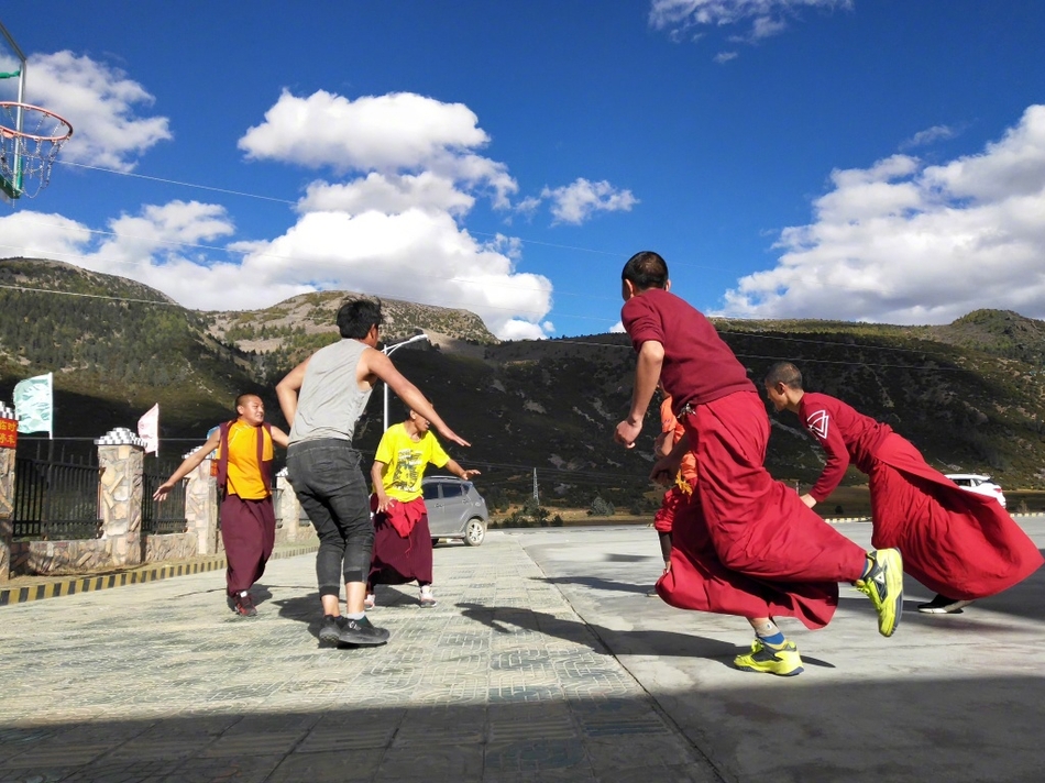 夕阳的余晖洒在简陋的水泥地球场上,给几位围在一起商讨战术的喇嘛镀上了一层温暖的金边。他们用手比划着,表情认真而放松,仿佛在进行一场神圣的仪式。
