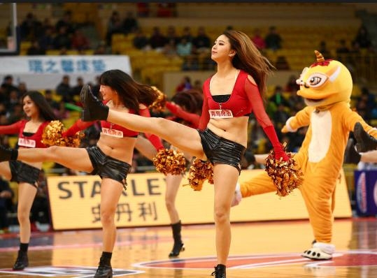 一名篮球宝贝双手撑地，身体呈现完美的“一”字形，汗水打湿了她额前的发丝，但她的目光依旧坚定，嘴角带着自信的微笑，在灯光的照耀下，这一刻的柔韧与力量感并存，令人动容。